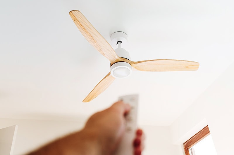 How to Choose the Right Ceiling Fan. A person turning on a ceiling fan.