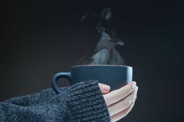 Image of someone holding a cup of coffee or tea. 5 Ways to Keep Warm When the Power Goes Out.